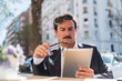 © David Naval/ADDICTIVE STOCK - Serious aged male entrepreneur in business style clothing working with digital tablet while sitting at outdoors cafe on blurred background