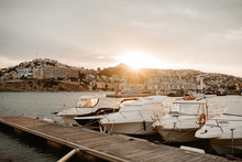 Sea Port With White Yachts And Boats In City With Buildings On Hills At Beautiful Sunset With Cloudy Sky
