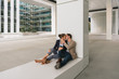 © Hernandez And Sorokina/ADDICTIVE STOCK - Male manager hugging and kissing girlfriend while sitting outside office building on city street after work