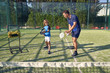 © PHILIPPE DEGROOTE/ADDICTIVE STOCK - Adult man showing boy how to hold paddle and hit ball during tennis training on sunny day on court