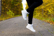 Low angle view of woman legs in white stylish sneakers over ankle in air. Jumping person. Casual sporty shoes. Concept of trends in footwear for autumn and spring.