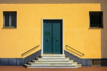 Closeup Of An Entrance Of A Yellow Building With Green Doors And Windows