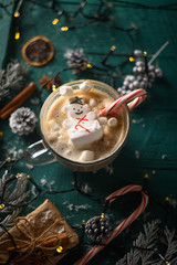 Wall Mural - Christmas and New Year. Marshmallow snowman in hot latte in a mug. Vertical composition on a green background.