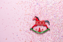 Christmas Toy Of Rocking Horse On Pink Background With Glitter. Flat Lay