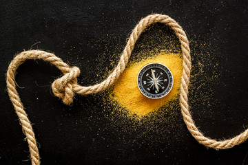 Wall Mural - Goal achievement concept. Compass near rope with knot on black background top view copy space
