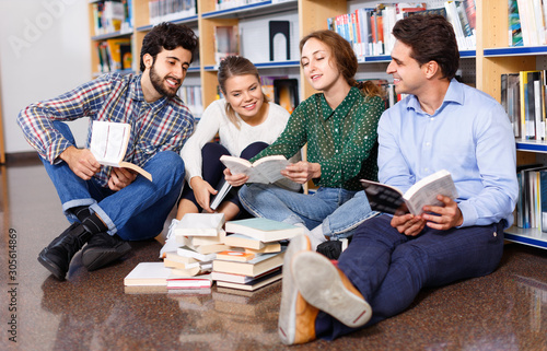Cuadros en Lienzo Group of happy students studying together in library, sitting on floor on backgr
