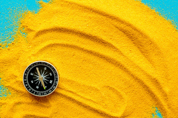Wall Mural - Travel concept. Compass on yellow sand background top view copy space