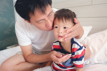 Fever, Asian father checking temperature, Parent measuring temperature of his ill kid, Little 3 years old toddler boy child gets fever sitting in bed while dad take care of him in bedroom at home