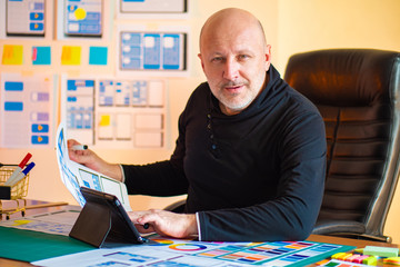 Wall Mural - designer is looking at the camera. ux designer. man at the desk. office designer mobile applications
