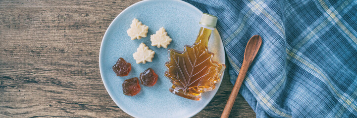 maple syrup bottle and pure soft sugar candy and taffy top view on kitchen table panoramic banner. c