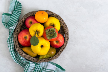 Wall Mural - Fruit basket on a light concrete background. Seasonal fruits are a source of vitamins and health. Copy space.