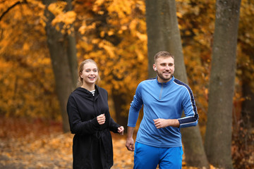 Canvas Print - Loving young couple running in autumn park