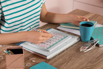 Canvas Print - Woman marking date in calendar at wooden table, closeup