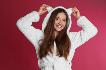 Wall Mural - Young woman in bathrobe with funny hood on crimson background