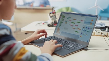 Smart Schoolboy Uses Laptop to Program Software for Robotics Engineering Class. Elementary School Science Classroom with Gifted Brilliant Children Working with Technology