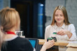 © Aleksandr - student girl pays order in cafe by credit card