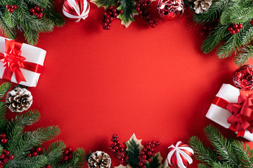 Christmas background concept. Top view of Christmas gift box red balls with spruce branches, pine cones, red berries star and bell on red background.