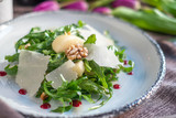 Fototapeta Tulipany - Fresh Salad with arugula, Parmesan cheese, potatoes and nuts on a white plate.