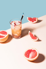 Fresh summer cocktail with pink grapefruit slices. Divided blue and beige bankground. Abstract conception.