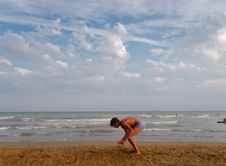 athletic teenager on the beach in jump on the background of the sea and sky