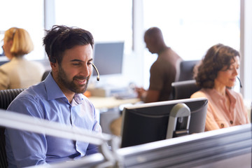 Businessman Wearing Telephone Headset Talking To Caller In Customer Services Department