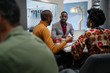 © JonoErasmus - Candid black african business team meeting in discussion sitting in office canteen
