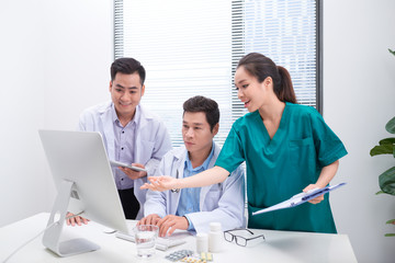 Wall Mural - Three doctors discussing patient files on office.