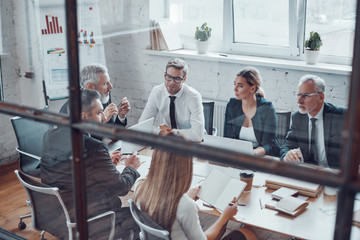 Canvas Print - Top view of coworkers discussing next business step while working together with colleagues in the modern office