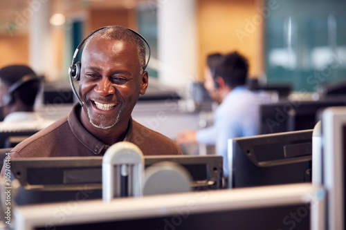 Fotografía Mature Businessman Wearing Telephone Headset Talking To Caller In Customer Servi