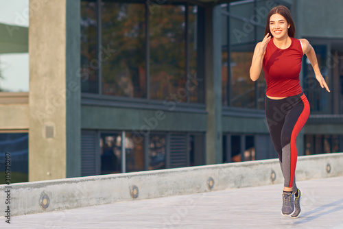 Fotomural Young woman exercising / running in urban park.