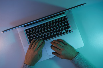 Aufkleber - Man working night online silver laptop in the color light on a table night background. Top view.