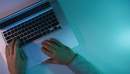 Aufkleber - Man working night online silver laptop in the color light on a table night background. Top view.