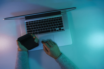 Aufkleber - Man working night online silver laptop and smart phone in the color light on a table night background. Top view.
