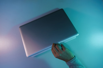 Aufkleber - Man open silver laptop night online in the color light on a table night background. Top view.