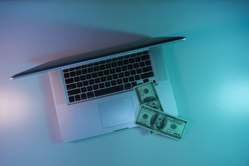 Aufkleber - Beautiful silver laptop and cash dollars banknote in the color light on a table and  background. Work night concept. Top view.
