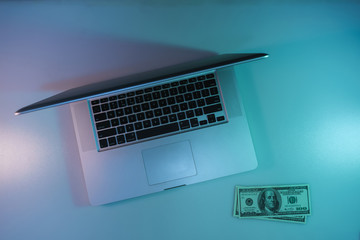 Aufkleber - Beautiful silver laptop and cash dollars banknote in the color light on a table and  background. Work night concept. Top view.
