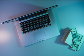Aufkleber - Beautiful silver laptop, notebook and cash dollars banknote in the color light on a table and  background. Work night concept. Top view.