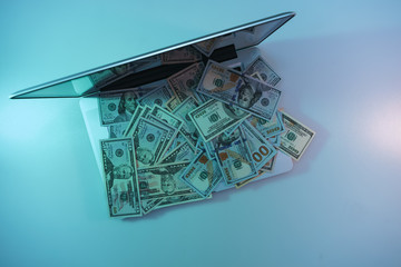 Poster - Beautiful silver laptop and cash dollars banknote in the color light on a table and  background. Work night concept. Top view.