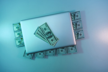 Aufkleber - Beautiful silver laptop and cash dollars banknote in the color light on a table and  background. Work night concept. Top view.