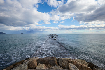 Wall Mural - A pier of stones, a pier going into the sea. Dramatic sky with dark, heavy clouds.