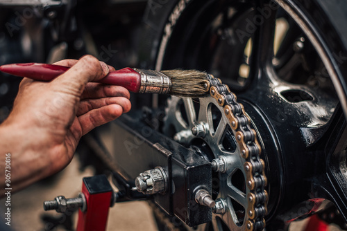 Fotomural Motorcycle maintenance, lubricating chain, close-up.