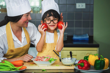 Wall Mural -  Asian woman young mother with son boy cooking salad mom sliced vegetables food son tasting salad dressing vegetable carrots and tomatoes bell peppers happy family cook food lifestyle kitchen