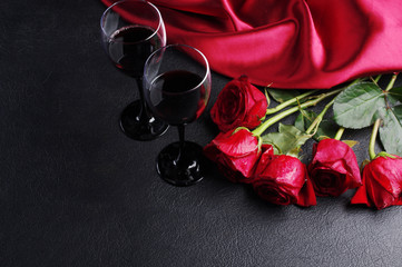 Wall Mural - Two glasses with red wine, five red roses and red drapery on black
