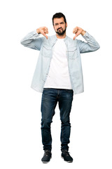 Wall Mural - Full-length shot of Handsome man with beard showing thumb down over isolated white background