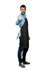 Wall Mural - Full-length shot of Man with apron with thumbs up because something good has happened over isolated white background