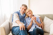 © Prostock-studio - Happy mature couple sitting on sofa and embracing