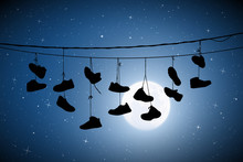 Shoes On Wires On Moonlit Night. Vector Illustration With Silhouette Of Old Shoes Hanging On Power Lines. Full Moon In Starry Sky