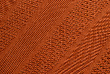 Orange Knitted Plaid Closeup. Knitted Texture With Diagonal Ornament. Detailed Warm Background Made Of Yarn. Natural Woolen Fabric, Fragment Of A Sweater For Design. Copy Space. View From Above