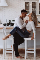 Wall Mural - Romantic christmas evening of a young couple. New year love story. Photo session of lovers in the kitchen.