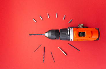 Top view of screw with batteries and different drills over blue background